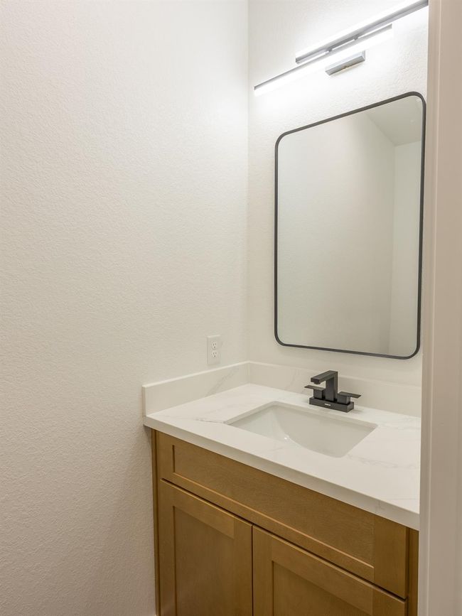 Tucked away for privacy, the powder bath offers a sleek quartz countertop, warm wood vanity, and bold matte black fixtures—perfect for guests. | Image 30