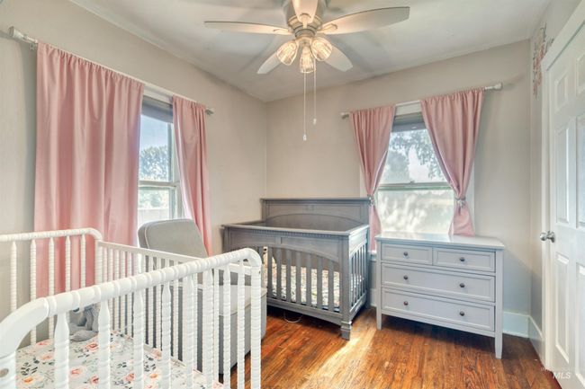 Bedroom featuring dark wood-style flooring, a crib, and ceiling fan | Image 22