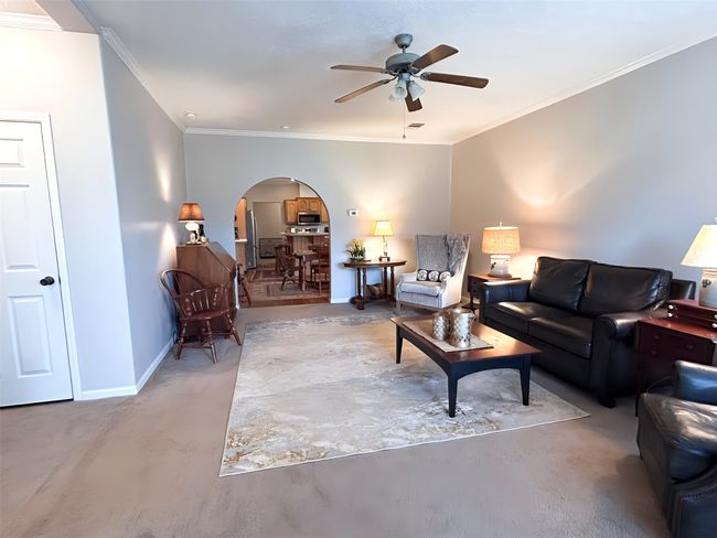 Living area featuring arched walkways, baseboards, crown molding, and a ceiling fan | Image 11
