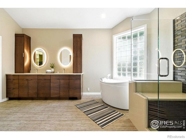 The updated primary bathroom includes a spa tub, large glass shower with glass tiles, and mirrors with LED dimmable lights and an anti-fog feature. | Image 12