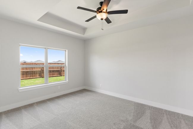 Carpeted spare room featuring a raised ceiling and a ceiling fan | Image 11