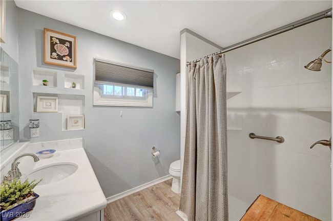 Bathroom with toilet, a shower with shower curtain, wood finished floors, and vanity | Image 35