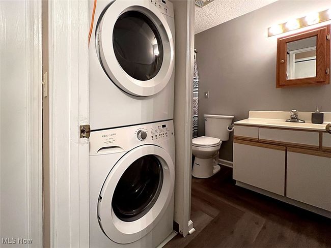 Laundry/full bathroom featuring stacked washer and dryer, dark wood-style floors, and a textured ceiling | Image 18