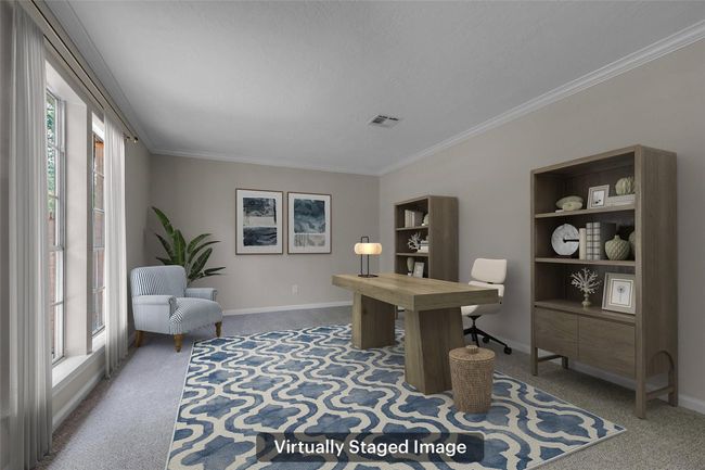 This virtually staged image shows a bright, spacious home office with large windows, neutral walls, and a cozy carpeted floor. It features a wooden desk, bookshelves, and a comfortable chair, creating an inviting workspace. | Image 7