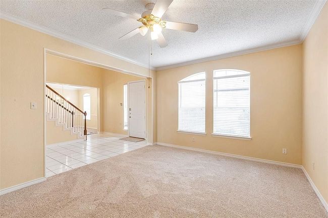 Spare room featuring carpet, stairway, a ceiling fan, crown molding, and a textured ceiling | Image 12