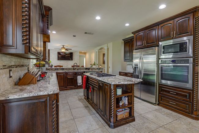 Kitchen featuring appliances with stainless steel finishes, backsplash, light tile patterned flooring, and recessed lighting | Image 13