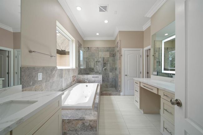 Primary bathroom features an oversized shower, a jetted tub, a vanity area and double sinks with a separate toilet room. | Image 21