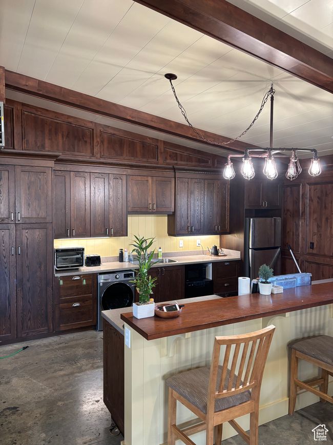 Kitchen with pendant lighting, a kitchen breakfast bar, stainless steel fridge, and washer / dryer | Image 62