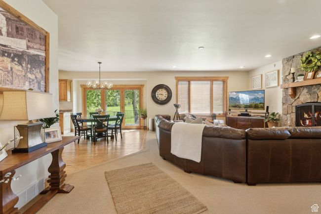 Living area featuring light colored carpet, a chandelier, a stone fireplace, and recessed lighting | Image 15