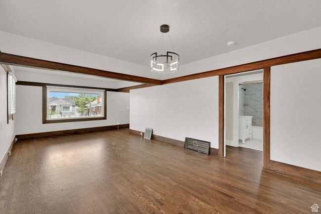 Spare room featuring a chandelier, wood finished floors, baseboards, and a smoke detector | Image 6