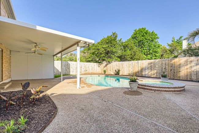 View of swimming pool featuring a patio area, a fenced backyard, ceiling fan, and a pool with connected hot tub | Image 7