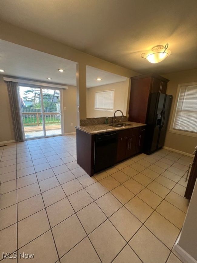 Kitchen with dark brown cabinets, sink, light tile flooring, and black appliances | Image 11