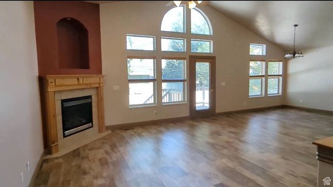 Doorway to outside with light wood-style flooring, a tile fireplace, ceiling fan, baseboards, and a chandelier | Image 6