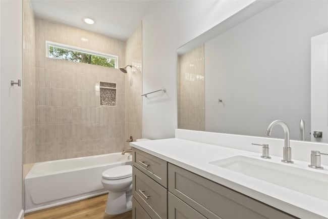 A stunning, spacious bathroom with a sleek vanity, a bath-shower combo, and radiant natural light. | Image 27