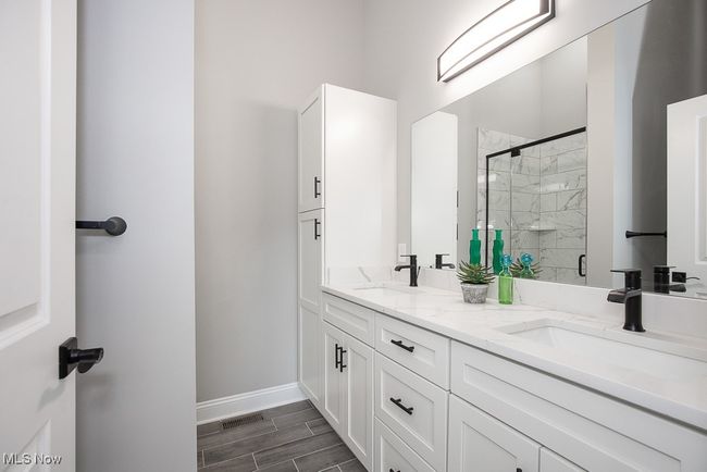 Bathroom featuring vanity with extensive cabinet space, double sink, and a shower with door | Image 29