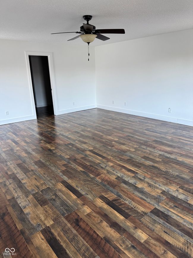 empty room with dark wood-type flooring, a textured ceiling, and a ceiling fan | Image 9