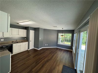 Kitchen featuring pendant lighting, sink, white cabinetry, black dishwasher, and dark hardwood / wood-style flooring | Image 3