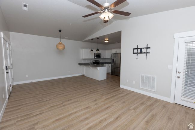 Unfurnished living room featuring lofted ceiling, a ceiling fan, baseboards, light wood-type flooring, and a sink | Image 5