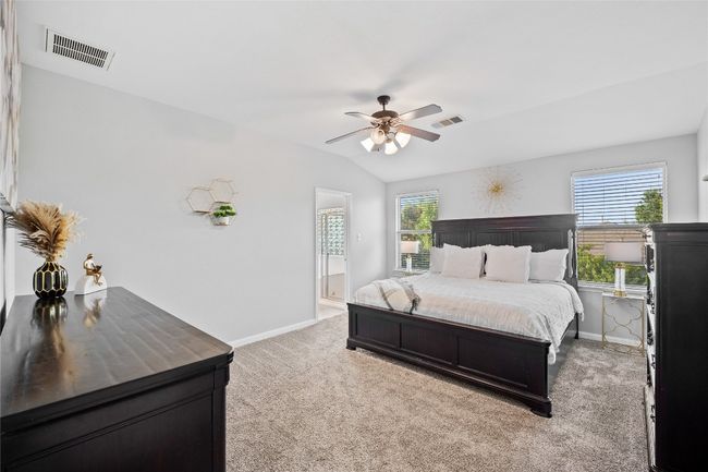 Bedroom with light colored carpet, vaulted ceiling, ceiling fan, and ensuite bathroom | Image 12