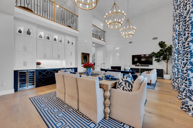 Living area featuring wine cooler, a high ceiling, light wood-style floors, a chandelier, and a high end fireplace | Image 16