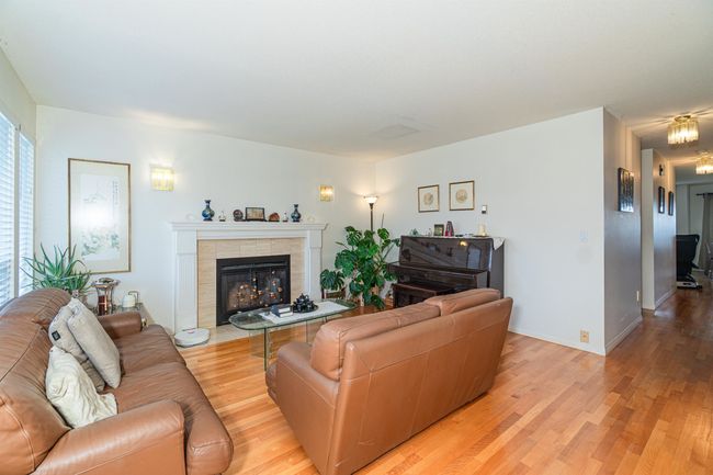 Living area featuring light wood finished floors, a tiled fireplace, and baseboards | Image 8