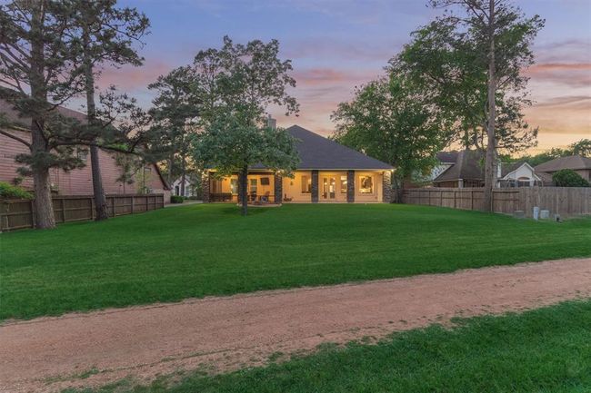 A nighttime view of the back of the home showcases the beautifully lit exterior, expansive yard, and direct access to the scenic walking trail—creating a peaceful and inviting outdoor retreat. | Image 38