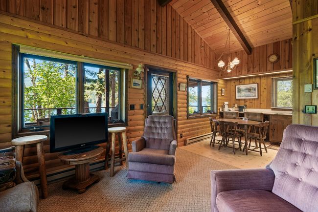 Living room with rustic walls, a chandelier, a baseboard heating unit, high vaulted ceiling, and a wood ceiling with exposed beams | Image 15
