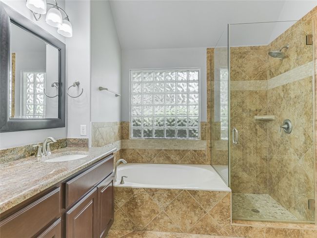 Soaking tub, separate shower, tile surround, and a beautiful glass block obscure window allows natural light and provides privacy. | Image 18