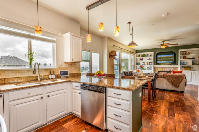 Kitchen with stainless steel dishwasher, a sink, a peninsula, white cabinets, and dark wood-style flooring | Image 11