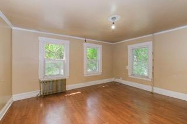 Unfurnished room featuring radiator, crown molding, and wood finished floors | Image 25