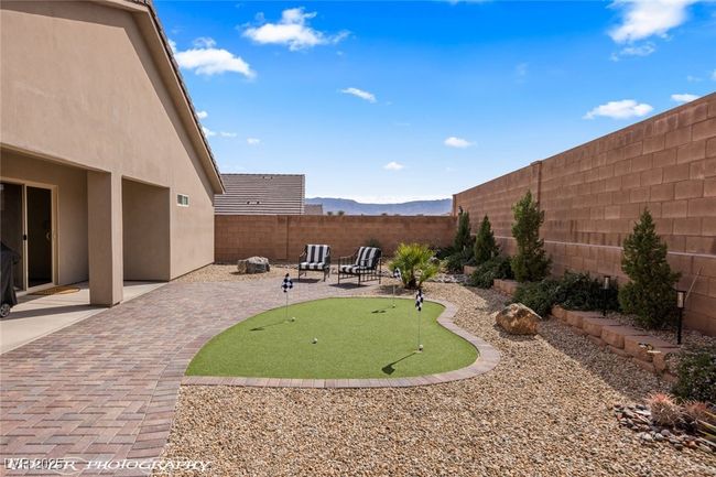Fenced backyard featuring an area to practice putting, a patio area, and a mountain view | Image 56