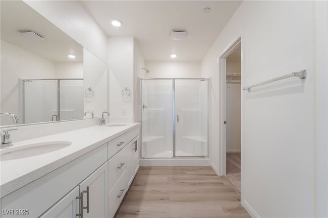 Bathroom featuring wood finished floors, a shower stall, double vanity, a walk in closet, and recessed lighting | Image 22