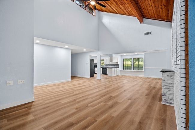 Unfurnished living room featuring a wood ceiling with exposed beams, a ceiling fan, light wood-style floors, a towering ceiling, and recessed lighting | Image 30