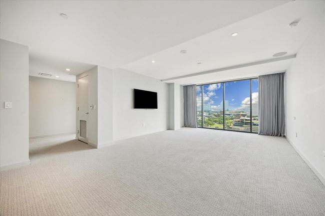 The large primary bedroom is an oasis of calm with carpet, automated drapes, and space for two separate seating areas. | Image 19