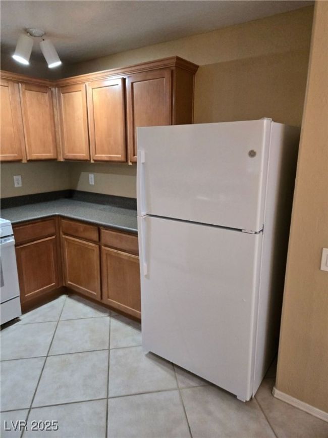 Kitchen featuring dark countertops, white appliances, and brown cabinets | Image 6