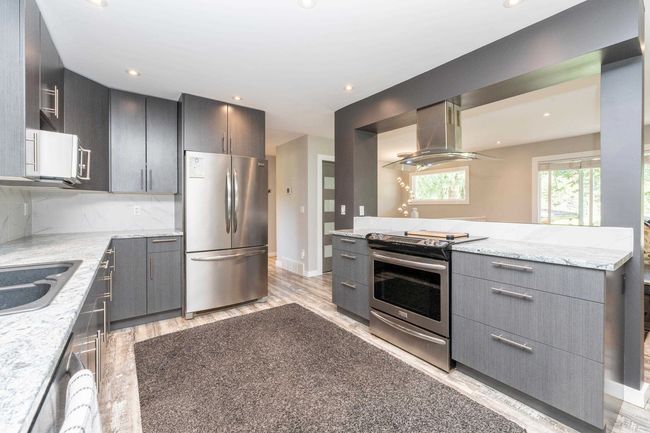 Kitchen featuring stainless steel appliances, island exhaust hood, light wood finished floors, gray cabinets, and modern cabinets | Image 9