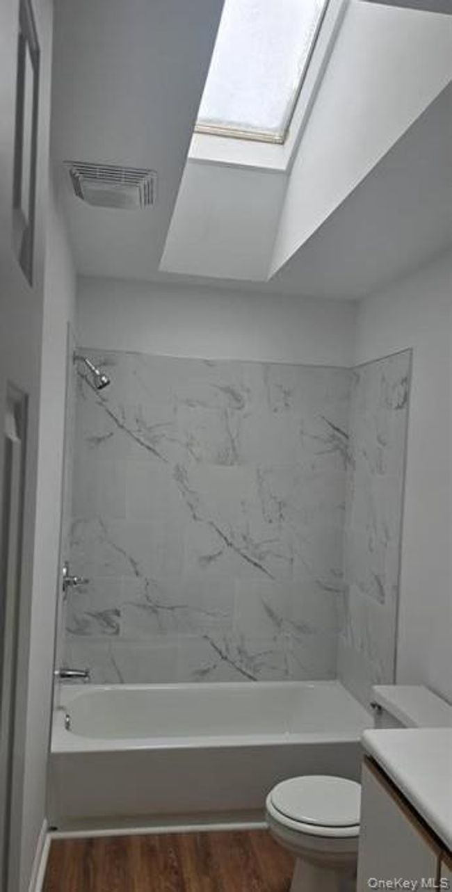 Full bathroom with vanity, shower / washtub combination, wood finished floors, and a skylight | Image 19
