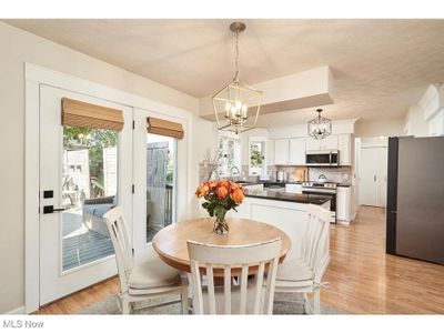 Dining room with sink, light wood-type flooring, an inviting chandelier, and a healthy amount of sunlight | Image 2