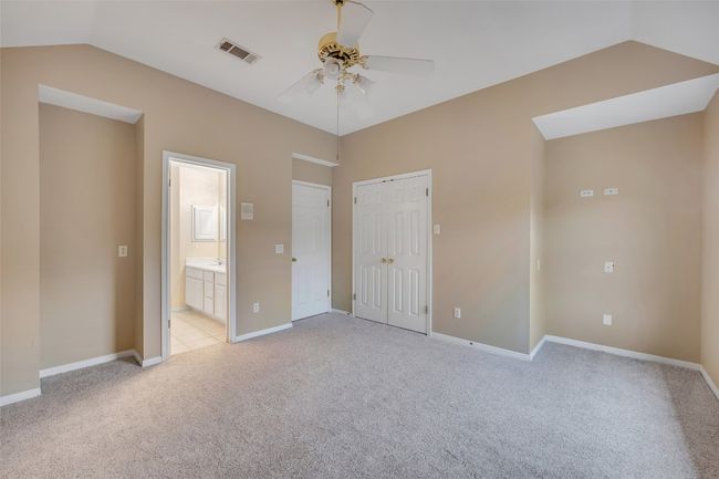 Unfurnished bedroom with light carpet, vaulted ceiling, ensuite bath, a closet, and a ceiling fan | Image 35