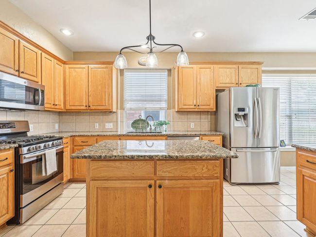 Kitchen with appliances with stainless steel finishes, plenty of natural light, light tile patterned floors, a kitchen island, and recessed lighting | Image 10
