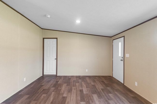 Spare room featuring wood finished floors, a smoke detector, ornamental molding, and vaulted ceiling | Image 23
