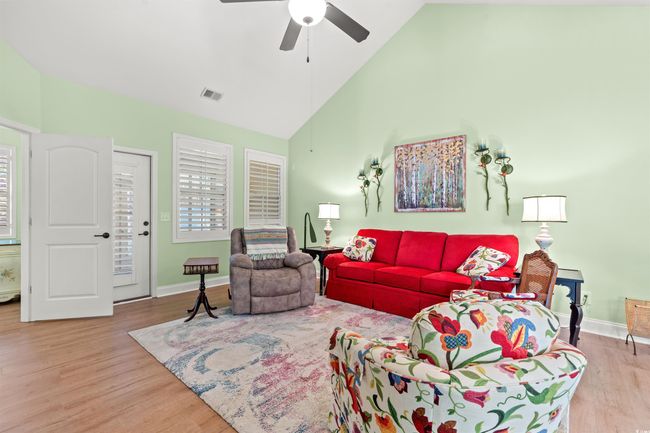 Living room with baseboards, visible vents, wood finished floors, and a ceiling fan | Image 13