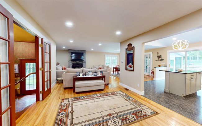 Living room featuring light wood finished floors, recessed lighting, french doors, baseboards, and a chandelier | Image 8
