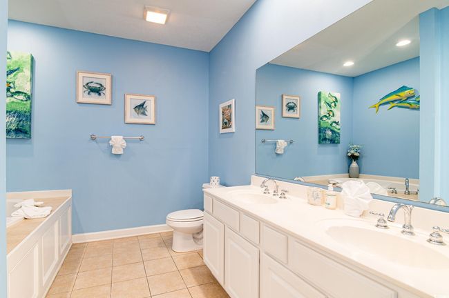 Bathroom with toilet, tile patterned flooring, a bath, baseboards, and double vanity | Image 31
