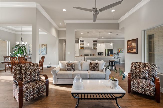 Light and open living area with wood look tile floors, and crown molding | Image 5