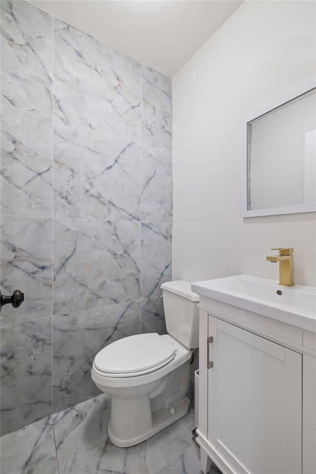 Bathroom featuring marble finish floor, toilet, vanity, and tile walls | Image 20