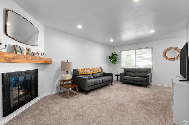 Living area featuring carpet flooring, recessed lighting, and a glass covered fireplace | Image 4
