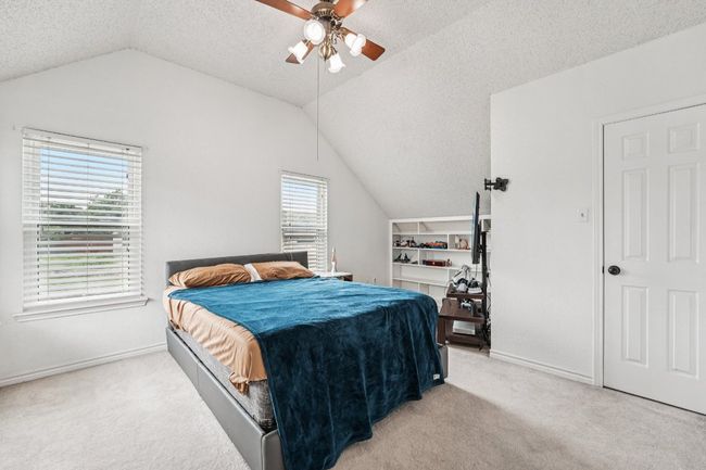 Bedroom featuring lofted ceiling, carpet floors, a textured ceiling, and ceiling fan | Image 22