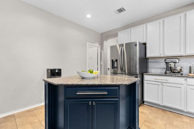 Kitchen with white cabinetry, light tile patterned floors, arched walkways, blue cabinetry, and recessed lighting | Image 11