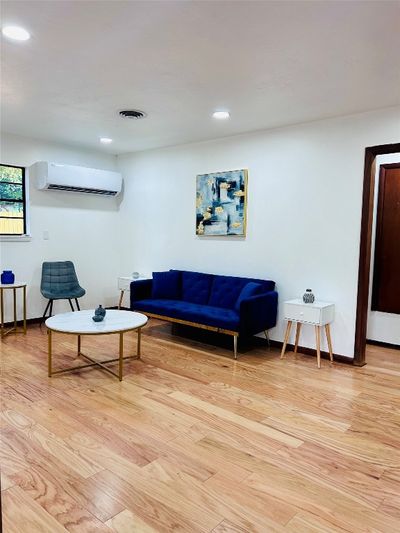 Living room with light wood-type flooring and a wall unit AC | Image 3